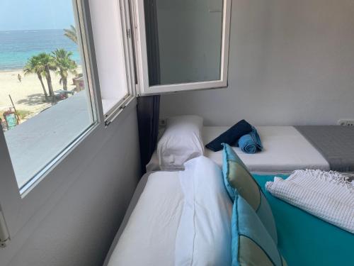 a room with two beds and a window with the beach at Thee Ibiza Suites - Ushuaia Beach in Playa d'en Bossa