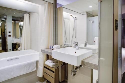 a white bathroom with a sink and a tub and a tubermott at Kaohsiung Chateau de Chine Hotel in Kaohsiung