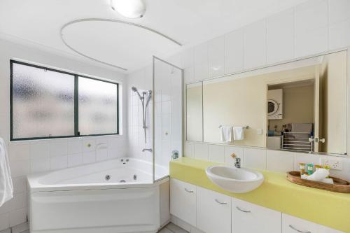 a white bathroom with a tub and a sink at Sunshine Towers Boutique Apartments in Maroochydore