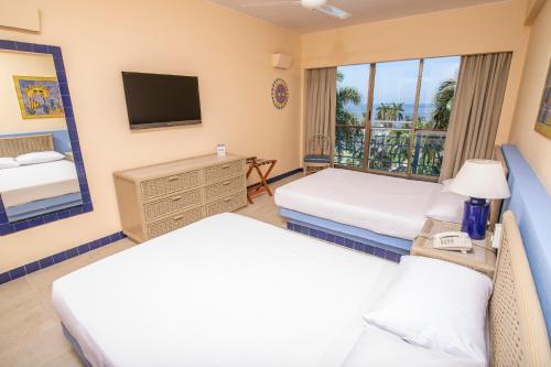 um quarto de hotel com duas camas e uma televisão em ZUANA BEACH RESORT SUITE PARA 6 PERSONAS 2 HABT 2BAÑOS em Santa Marta