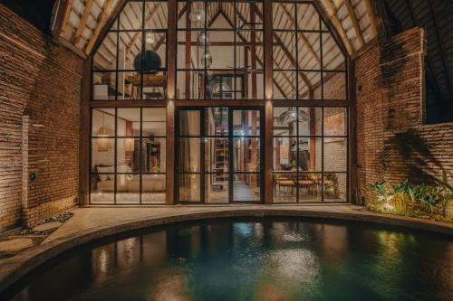 an indoor pool in a building with large windows at Sanctuary Villas in Ubud