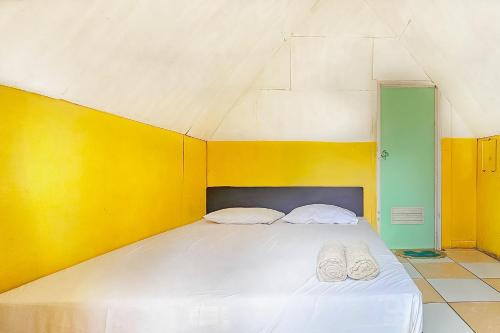 un letto con due cuscini bianchi in una stanza di Cigadog Residence Mitra Reddoorz a Ciwidey