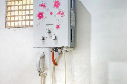 uma caixa eléctrica com flores ao lado de uma parede em Cigadog Residence Mitra Reddoorz em Ciwidey