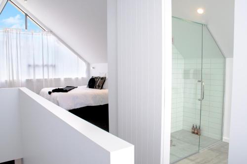 a white bedroom with a bed and a glass shower at Matakana Luxury Escapes in Matakana