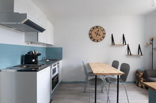 eine Küche mit einem Tisch und einer Uhr an der Wand in der Unterkunft Pretty ski nest in the city center in Gérardmer