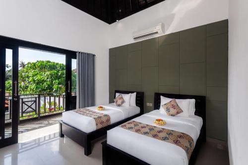 zwei Betten in einem Zimmer mit Balkon in der Unterkunft Maja Villa Batubelig by Pramana Villas in Canggu