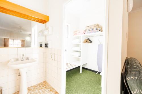Elle comprend une petite salle de bains pourvue d'un lavabo et d'un sol vert. dans l'établissement Landsborough Lodge Motel, à Barcaldine