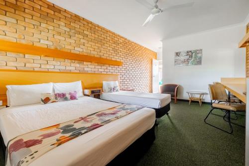 a hotel room with two beds and a brick wall at Landsborough Lodge Motel in Barcaldine