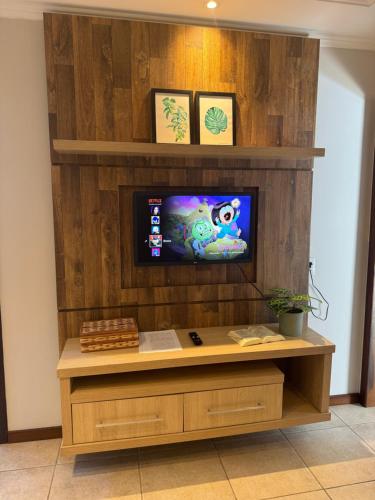 een entertainmentcentrum met een tv aan een houten muur bij Apartamento confortável próximo Vila Germânica in Blumenau