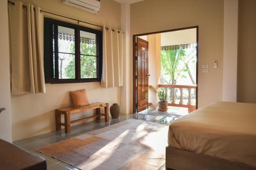 a bedroom with a bed and a chair and a window at Wichouda Cottage in Chiang Dao