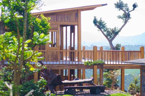 une maison en bois avec une terrasse et des arbres dans l'établissement KMI Homestay – Tea and Coffee, à Di Linh