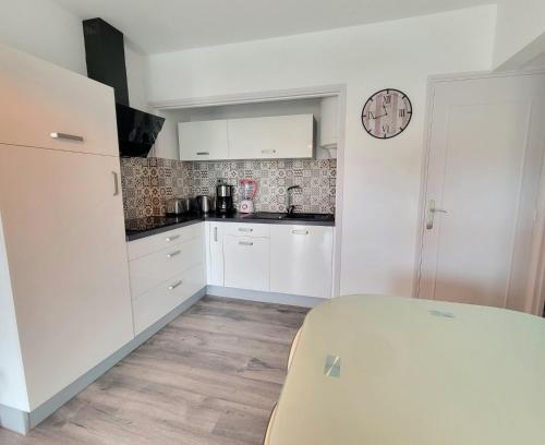 une cuisine avec des placards blancs et une horloge murale dans l'établissement Charming love nest near the sea, à Fréjus