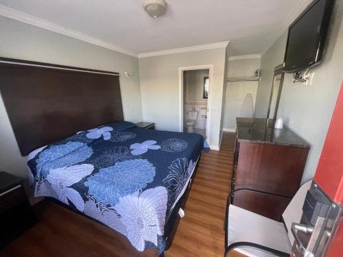 1 dormitorio con 1 cama con colcha azul y blanca en La Cienega Inn Motel, en Los Ángeles