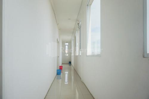 a long hallway with white walls and a long white floor at Sakura Kos RedPartner in Sukarami