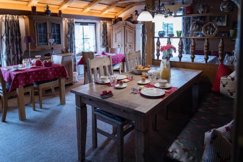 ein Esszimmer mit einem Holztisch mit Tellern und Geschirr darauf in der Unterkunft Gästehaus Sattlerhof in Bernau am Chiemsee