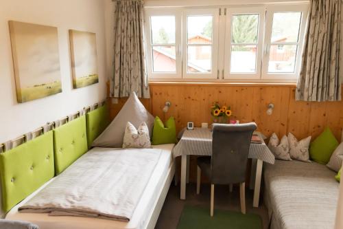 Cette chambre comprend 2 lits, une table et une fenêtre. dans l'établissement Gästehaus Sattlerhof, à Bernau am Chiemsee