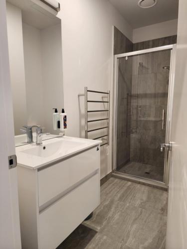 a white bathroom with a sink and a shower at U Suites on Victoria in Wellington