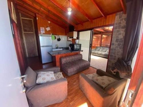 a living room with couches and a kitchen at Cabañas maule in Coronel