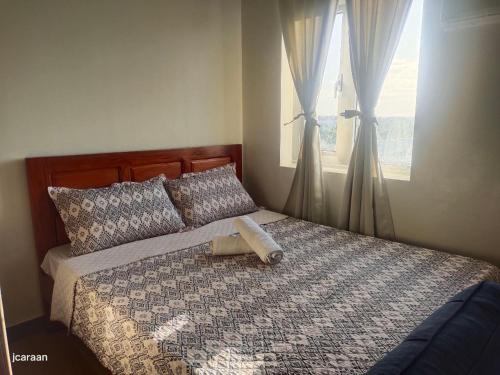 łóżko z drewnianym zagłówkiem i oknem w obiekcie Happy Stays A - Sunset View at SMDC Hope Residences w mieście Trece Martires