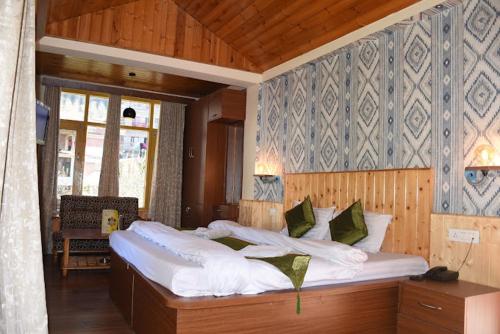 a large bed with white sheets and pillows in a room at Hotel Seraj International , Aleo Hill View in Manāli