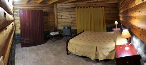 ein Schlafzimmer mit einem Bett in einem Blockhaus in der Unterkunft Hosteria Al Paraiso in Villa Pehuenia