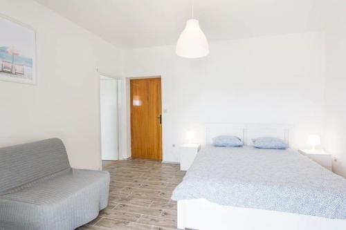 um quarto branco com uma cama e uma cadeira em Wohnung in Pašman mit Terrasse, Grill und Garten und Meerblick em Pasman