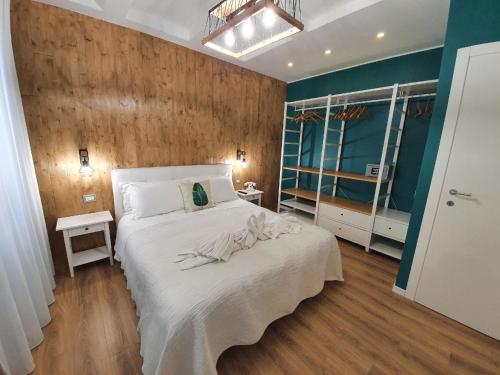 een slaapkamer met een wit bed en een houten muur bij Appartement in Sottomarina mit Terrasse in Chioggia