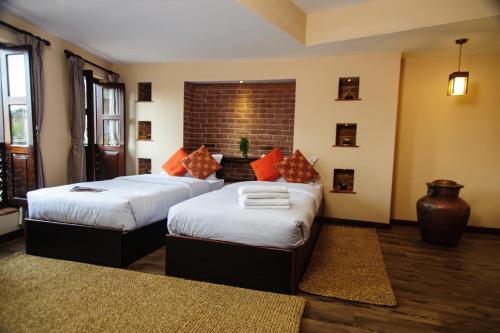 1 dormitorio con 2 camas y pared de ladrillo en Thagu Chhen, a Boutique Hotel, en Bhaktapur