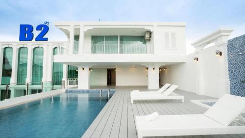 a house with a swimming pool and two white chairs at B2 Phuket Premier Hotel in Kathu