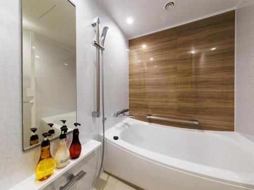 W łazience znajduje się biała wanna i duże lustro. w obiekcie Hotel Dream Gate Maihama Annex w Tokio
