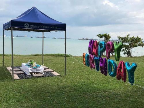 a sign for a party with a table and an umbrella at Glamping kaki singapore-Standard medium bell tent in Singapore