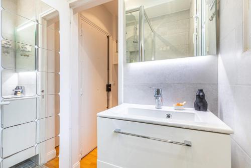ein Badezimmer mit einem weißen Waschbecken und einem Spiegel in der Unterkunft GuestReady - Blue Nest near Le Parc des Princes in Boulogne-Billancourt