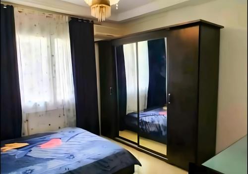 a bedroom with a bed and a cabinet with a mirror at Appartement 141m2 Moderne Haut Standing de 3 Chambres - Internet Fibre à Ennasr 2 - Idéal pour Famille - Service Navette in Burj at Turkī