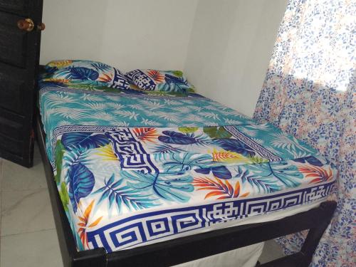 a bed in a room with a flowered sheet at Mágica Cabaña familiar cerca al mar in Coveñas