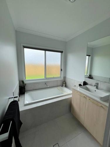 a bathroom with a tub and a sink and a window at Wait and Sea Bargara in Bargara