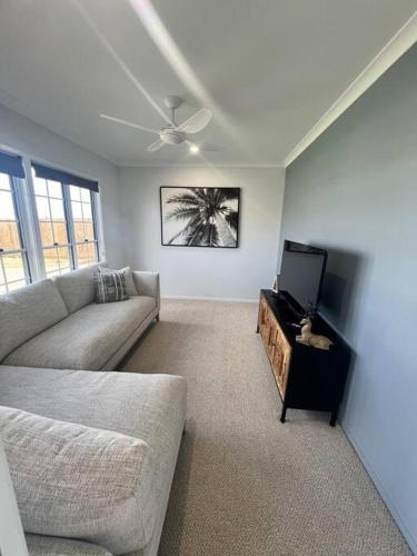 a living room with a couch and a tv at Wait and Sea Bargara in Bargara