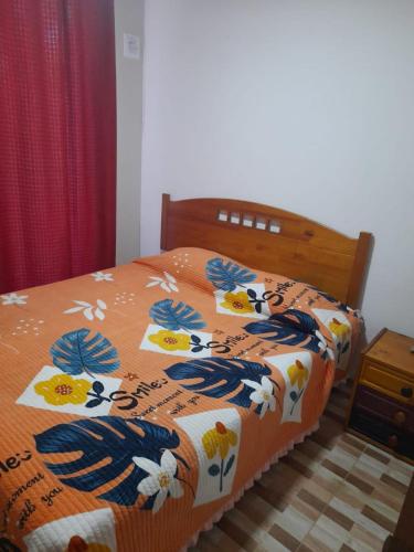 Una cama con una manta naranja con flores. en Departamento en el Tabo, en El Tabo