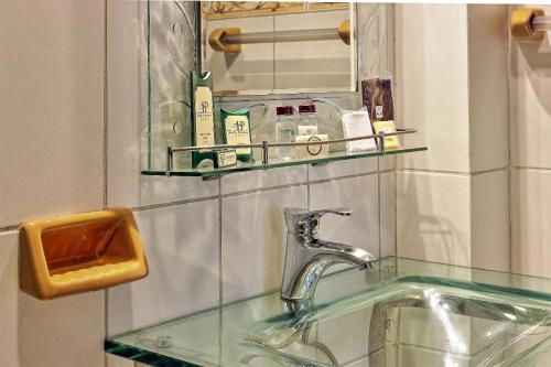 ポトシにあるHostal Patrimonio - Potosiのバスルーム(ガラスのカウンタートップと鏡付きの洗面台付)