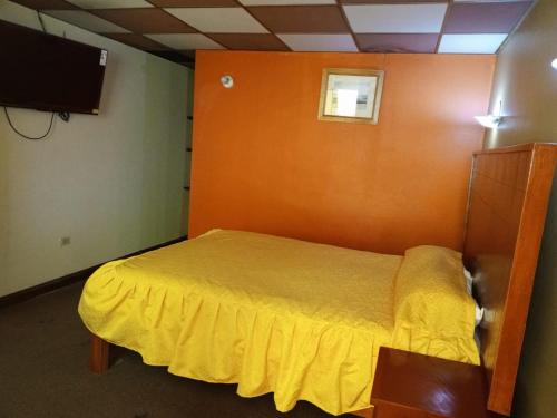 a bedroom with a bed with a yellow bedspread at TAWA INTI HOSTEL in Puno