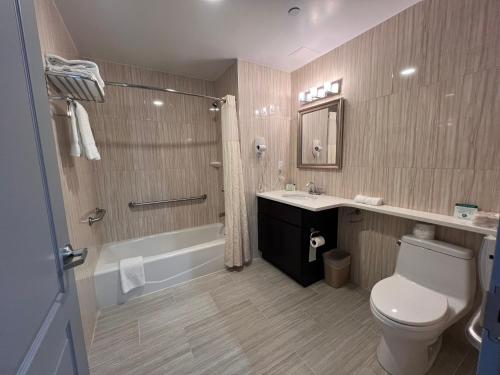 y baño con aseo, lavabo y ducha. en Grandview Hotel New York, en Queens