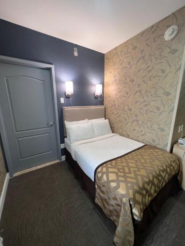 een kleine hotelkamer met een bed en een muur bij Grandview Hotel New York in Queens