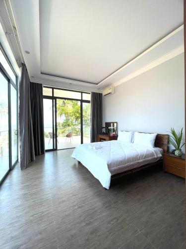 a bedroom with a large bed and large windows at Khalid’s House at the East coast in Phu Quoc
