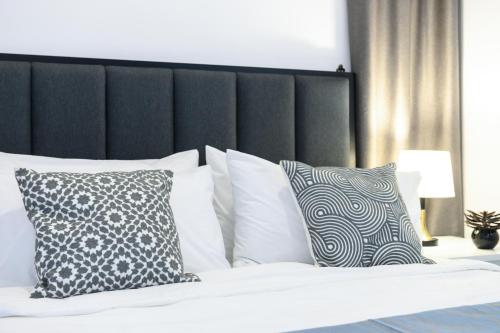 a bed with white pillows and a black headboard at Grace Suite @ The Shore KK in Kota Kinabalu