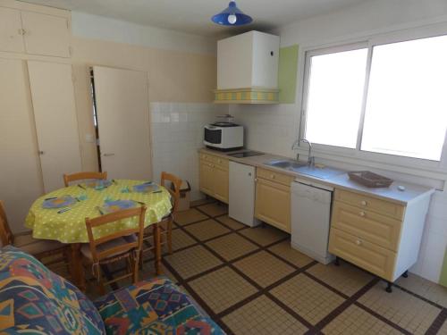 une cuisine avec une table et un évier et une table et des chaises dans l'établissement Maison de vacances à 100m de la plage, 4 pers, jardin, stationnement - Notre-Dame-de-Monts - FR-1-540-257, à Notre-Dame-de-Monts