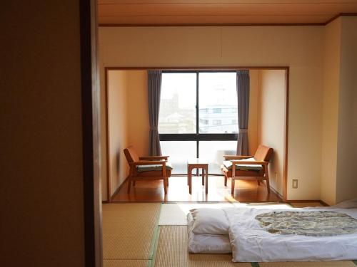 1 dormitorio con cama, sillas y ventana en ビジネス旅館 越後家 en Soka