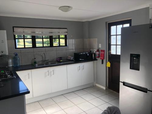 a kitchen with white cabinets and a refrigerator at Faithlands Self-Catering Cottages in Port Elizabeth
