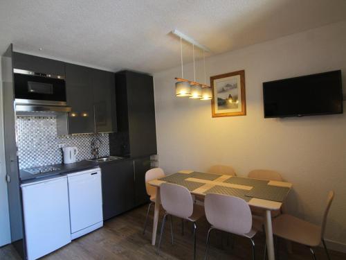 une cuisine et une salle à manger avec une table et des chaises dans l'établissement Appartement cosy avec balcon, piscine et sauna - Idéalement situé près des pistes - L'Alpe d'Huez - FR-1-405-358, à Huez