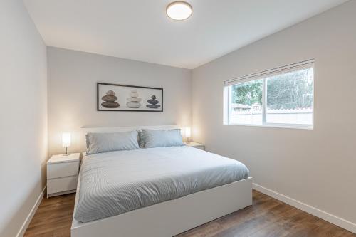 a white bedroom with a bed and a window at Beautifully remodeled Rambler in South Seattle in Seattle