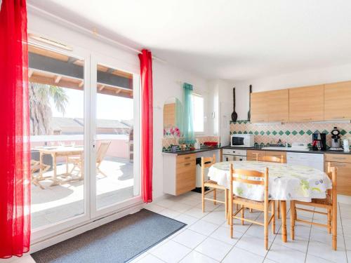 une cuisine avec une table et une salle à manger avec un balcon dans l'établissement Villa climatisée avec terrasse, cuisine d’été et WIFI – Proche plage à Narbonne - FR-1-409-261, à Narbonne