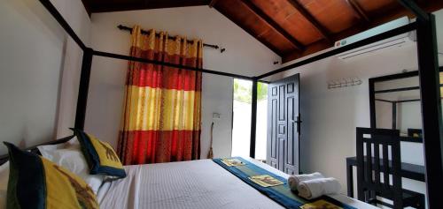 アルガムベイにあるSurf And Stay Arugam Bayのベッドルーム(カラフルなカーテン付きの天蓋付きベッド1台付)